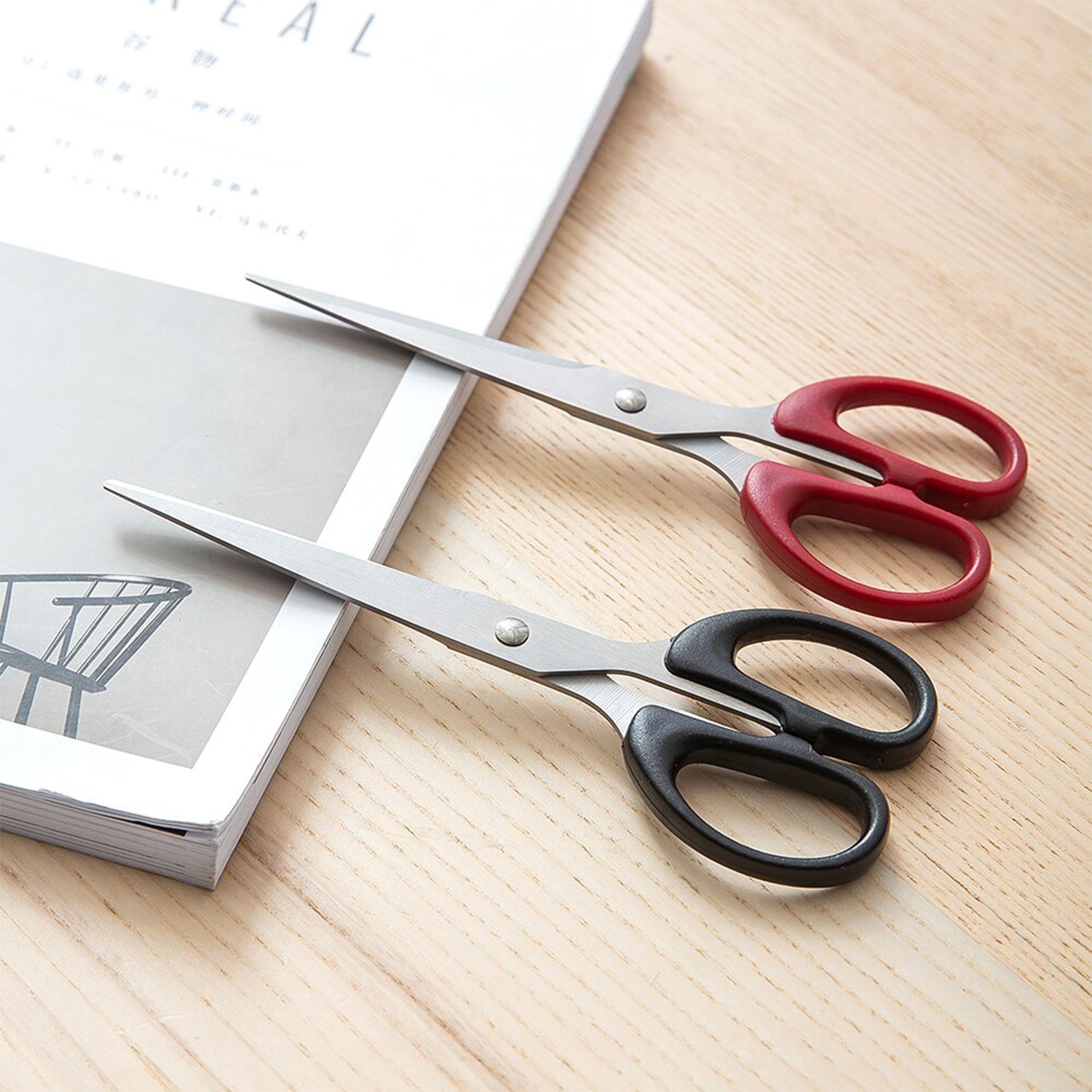 Top-down view of the scissors, emphasizing their stainless steel blades and plastic handle grip